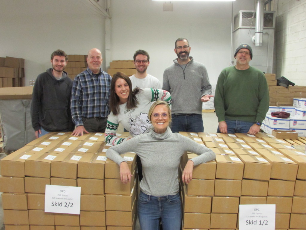 Posing next to a pallet of stacked cardboard boxes, the DTE Energy Volunteer team smiles for the camera.