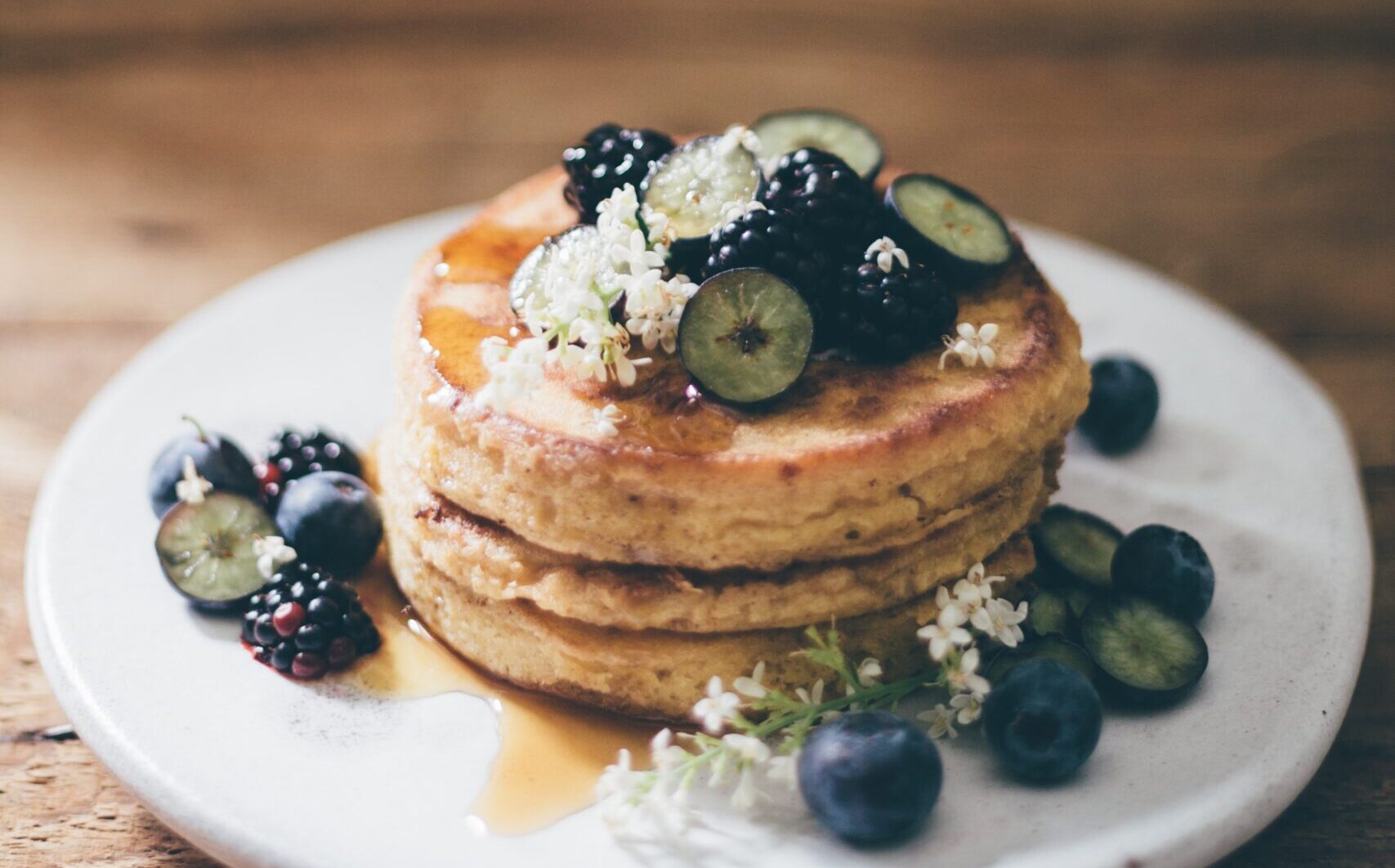 Pancakes with blueberries, syrup and flowers for garnish