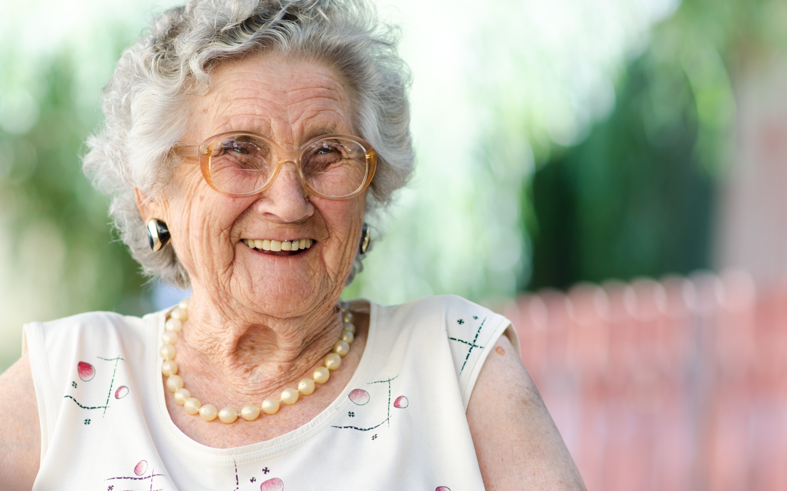 A senior woman smiles with glasses on.