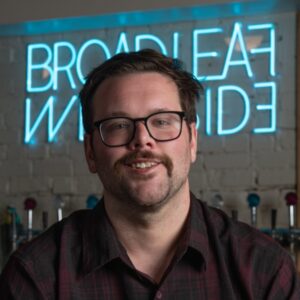 Chef Ryan McClure in front of a neon sign that says "Broadleaf Westside"