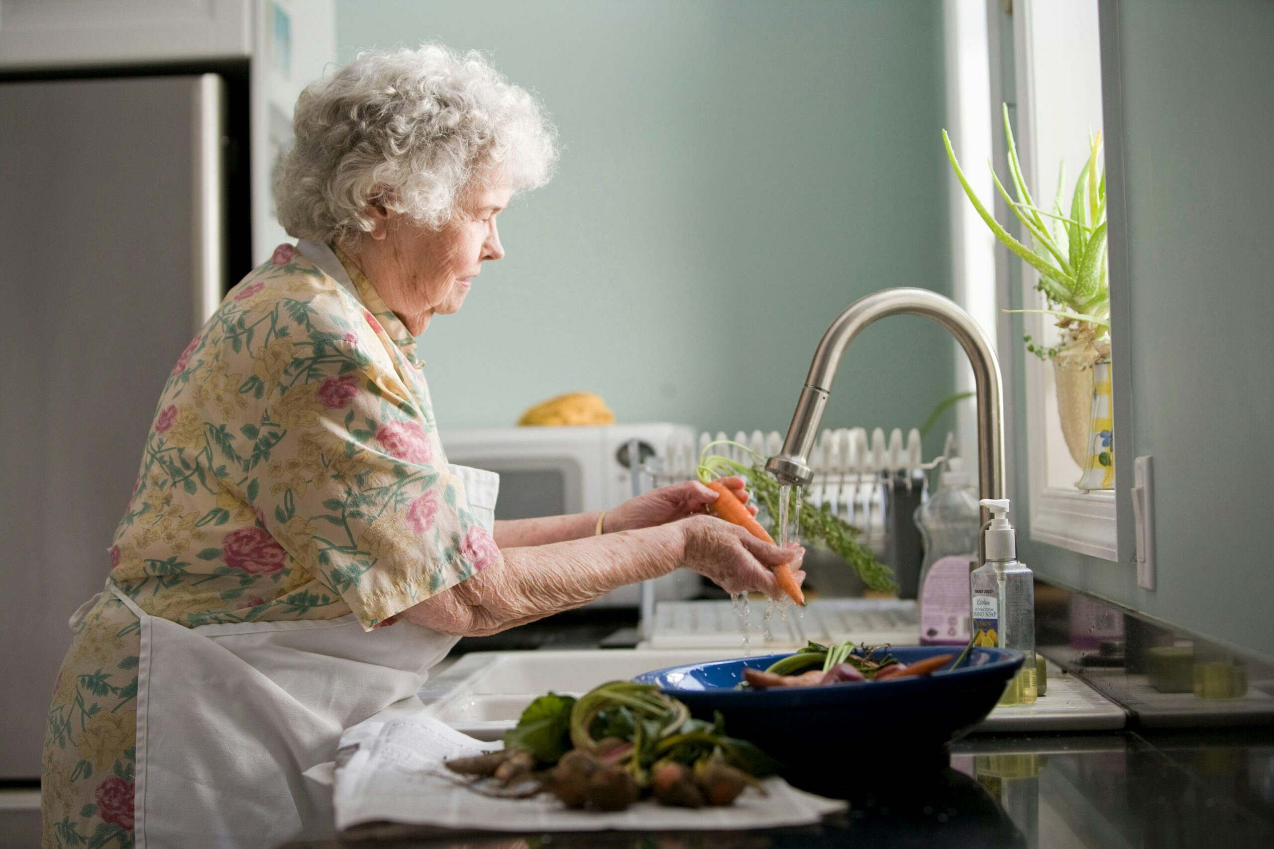 Woman washing vegetables at her kitchen sink.