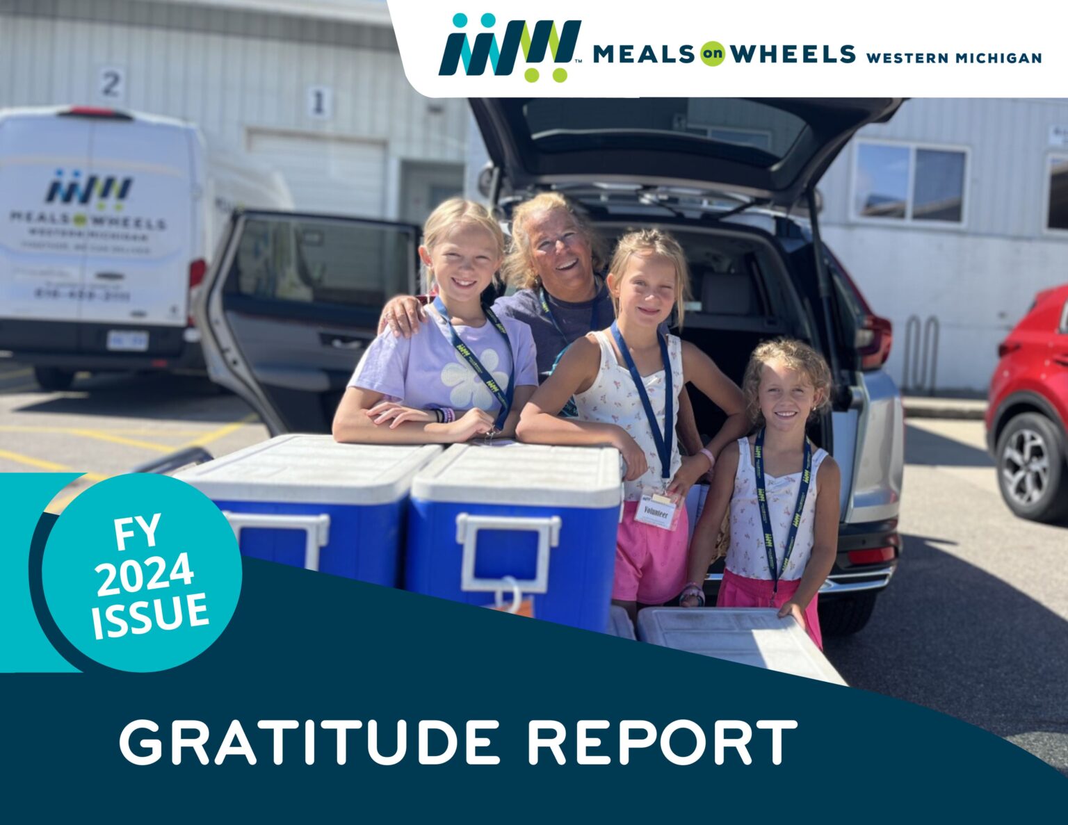 A smiling group with one woman and three children poses at an open car trunk behind a table with blue coolers non top. Text overlay reads "FY 2024 Issue: Gratitude Report."