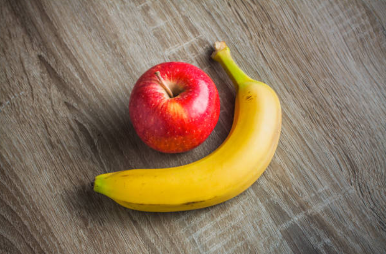 A banana and apple sitting on a table.